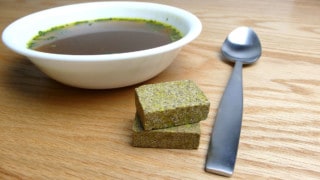 beef bouillon cubes sitting beside a bowl of liquid beef broth