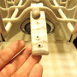 inspecting the holes in a dishwasher spray arm